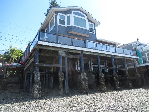 Waterfront house supported on piles above the rocky shoreline.
